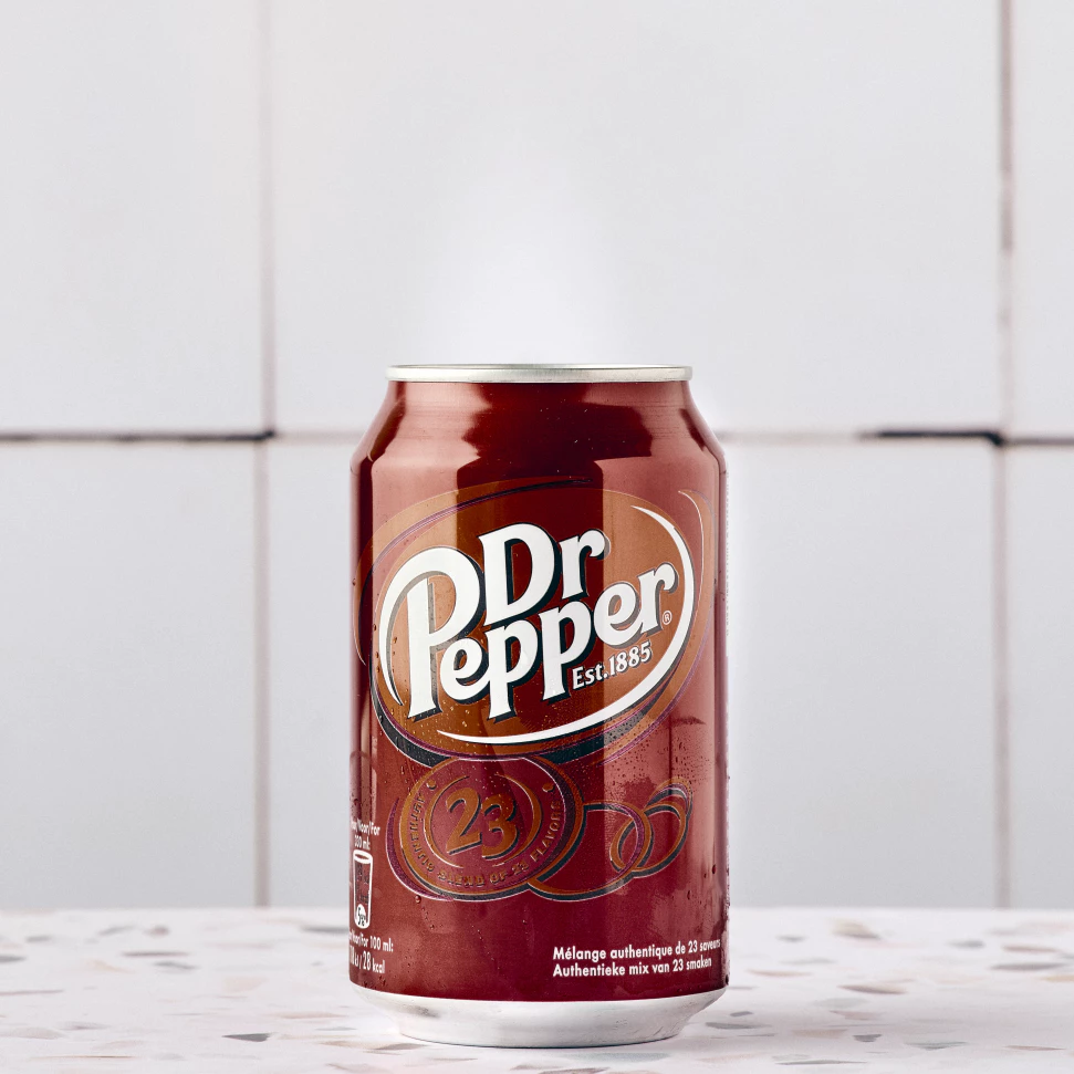 Une cannette de Dr Pepper posé sur un sol carrelé.