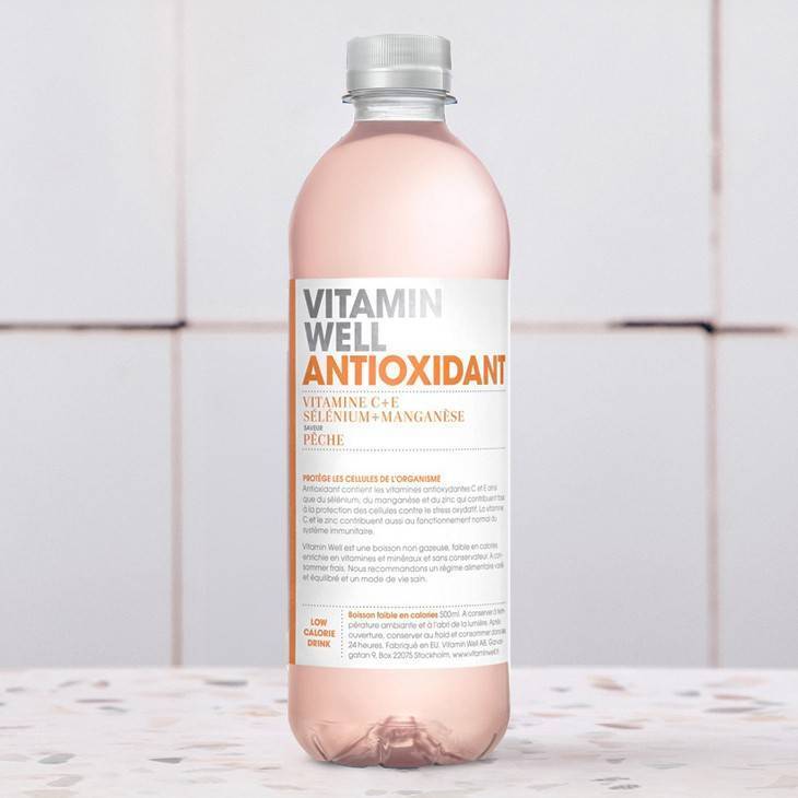 Une bouteille de boisson aromatisée aux vitamines et aux antioxydants avec de la vitamine C, du sélénium et du manganèse sur une surface à motifs.