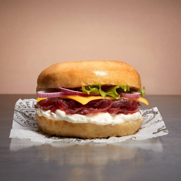 Un sandwich avec de la viande et du fromage sur un morceau de papier.
